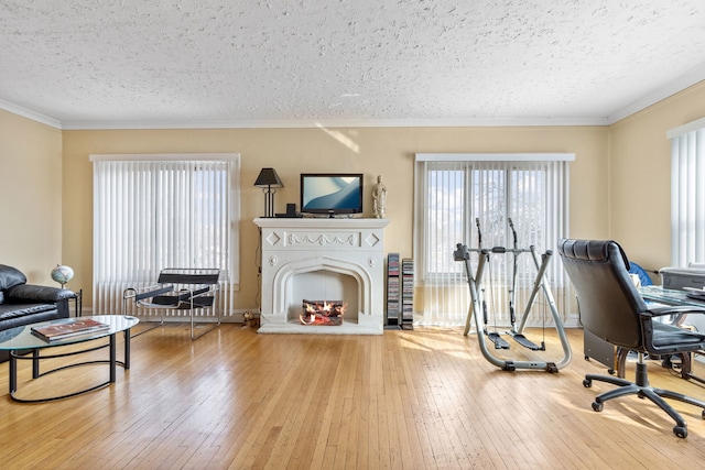 office area with ornamental molding, a warm lit fireplace, a textured ceiling, and hardwood / wood-style flooring