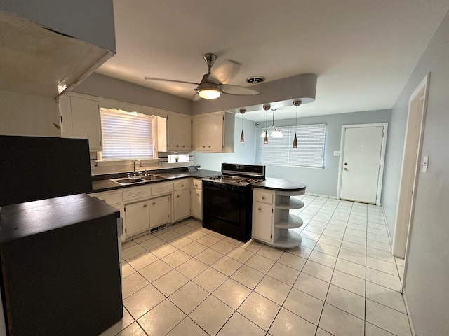 kitchen featuring black stove, sink, hanging light fixtures, light tile patterned floors, and ceiling fan