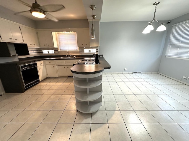 kitchen featuring sink, hanging light fixtures, light tile patterned floors, black dishwasher, and ceiling fan with notable chandelier