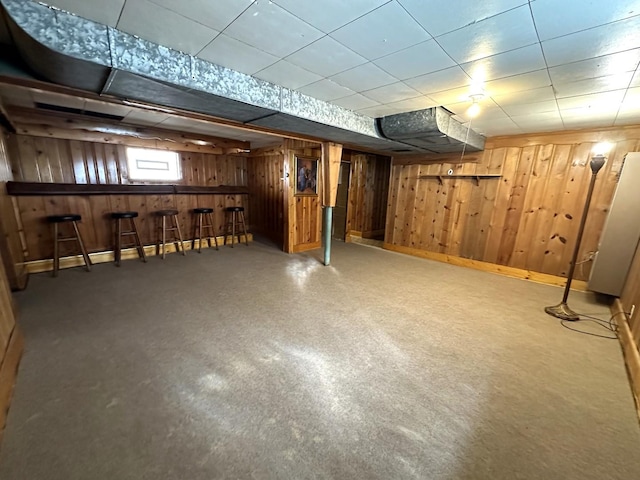 basement featuring indoor bar and wooden walls