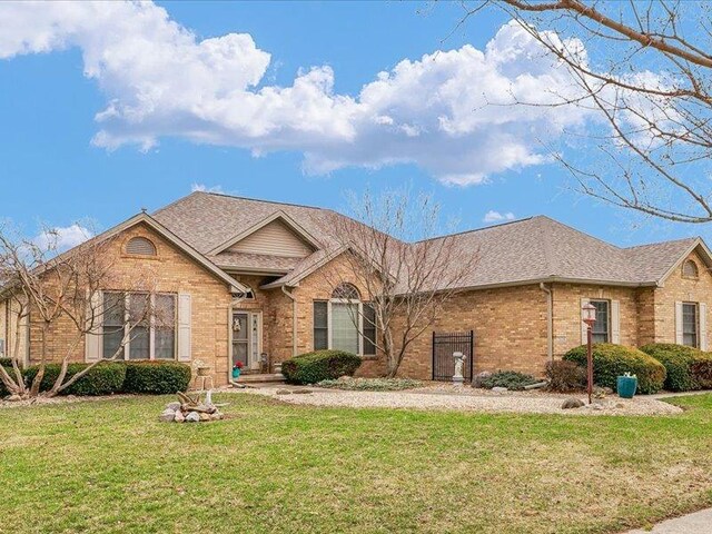 ranch-style house featuring a front yard, brick siding, and a shingled roof