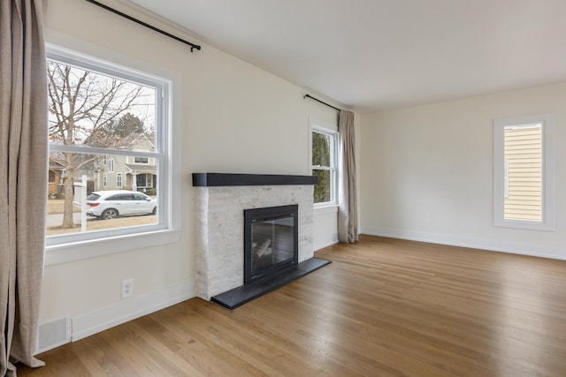 unfurnished living room featuring wood finished floors, a fireplace, visible vents, and baseboards