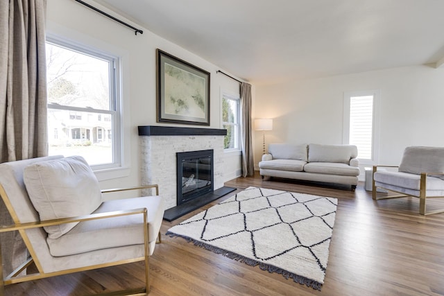 living room with a stone fireplace and wood finished floors