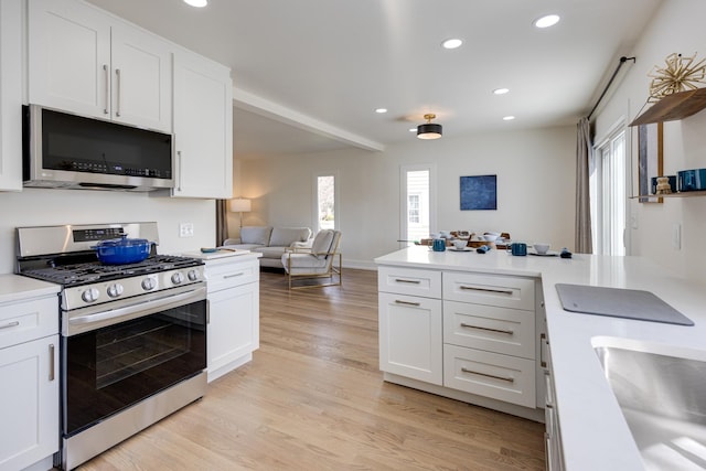 kitchen with white cabinets, light countertops, appliances with stainless steel finishes, recessed lighting, and light wood finished floors