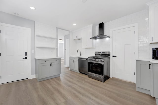 kitchen with stainless steel appliances, light hardwood / wood-style flooring, wall chimney range hood, and decorative backsplash