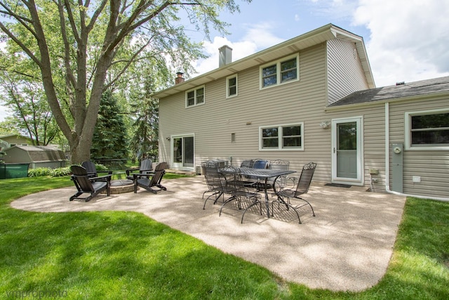 rear view of house with a patio, a lawn, and a fire pit