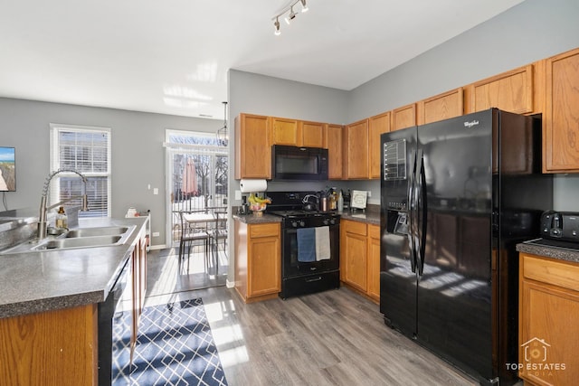 kitchen featuring sink, track lighting, pendant lighting, hardwood / wood-style floors, and black appliances