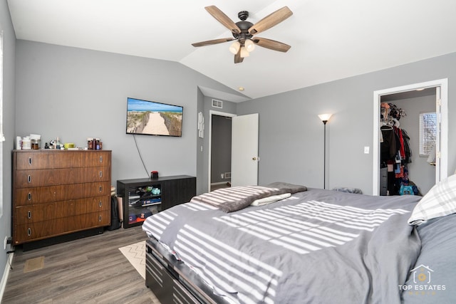 bedroom with vaulted ceiling, wood-type flooring, a walk in closet, ceiling fan, and a closet