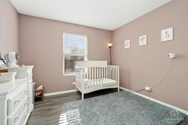 bedroom with a nursery area and dark wood-type flooring