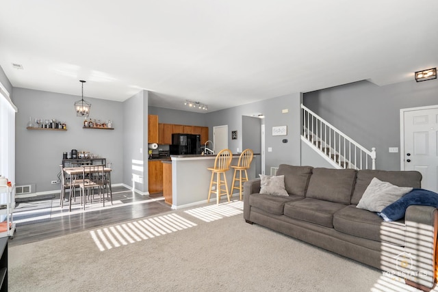 living room with an inviting chandelier, rail lighting, and light wood-type flooring