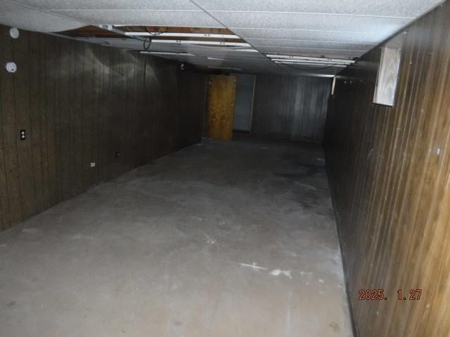 basement featuring a drop ceiling and wood walls