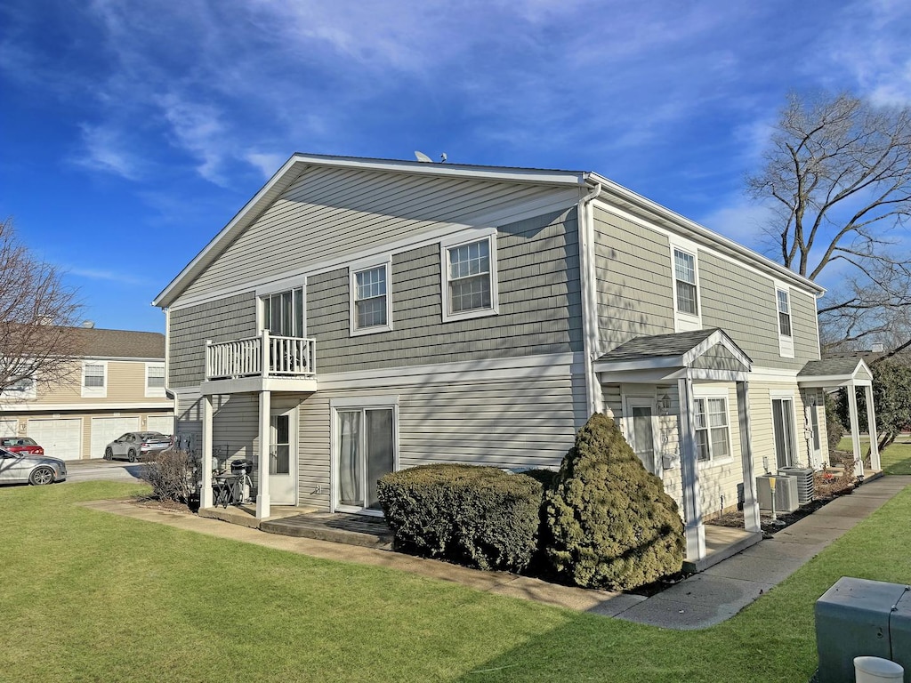 back of house featuring a balcony and a lawn