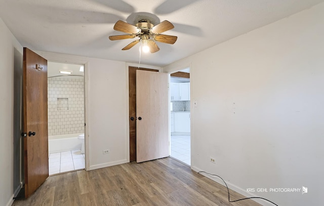 unfurnished bedroom with ensuite bath, ceiling fan, and light wood-type flooring