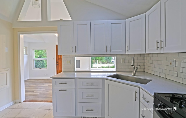 kitchen with vaulted ceiling, sink, white cabinets, and black gas range