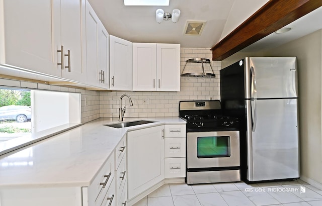 kitchen featuring appliances with stainless steel finishes, lofted ceiling, sink, white cabinets, and backsplash