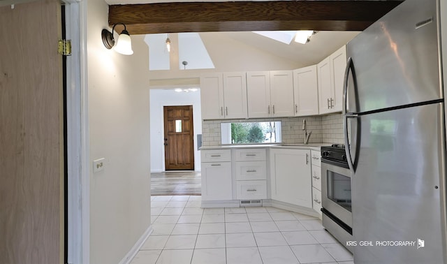 kitchen with sink, white cabinetry, lofted ceiling with skylight, stainless steel appliances, and decorative backsplash