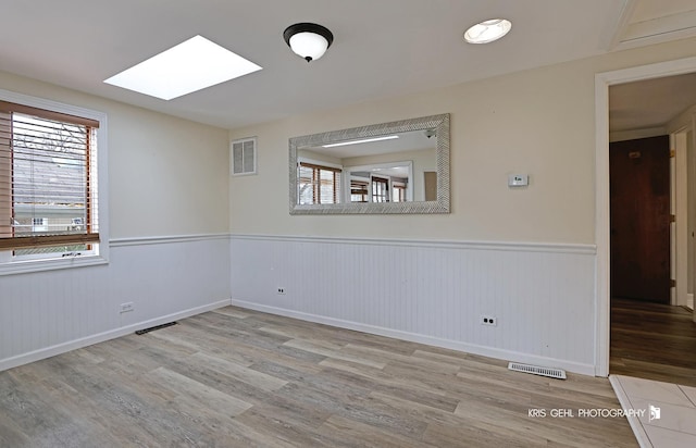 spare room featuring hardwood / wood-style floors and a skylight