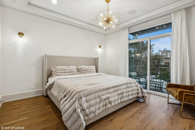 bedroom with an inviting chandelier, wood-type flooring, access to exterior, and a tray ceiling