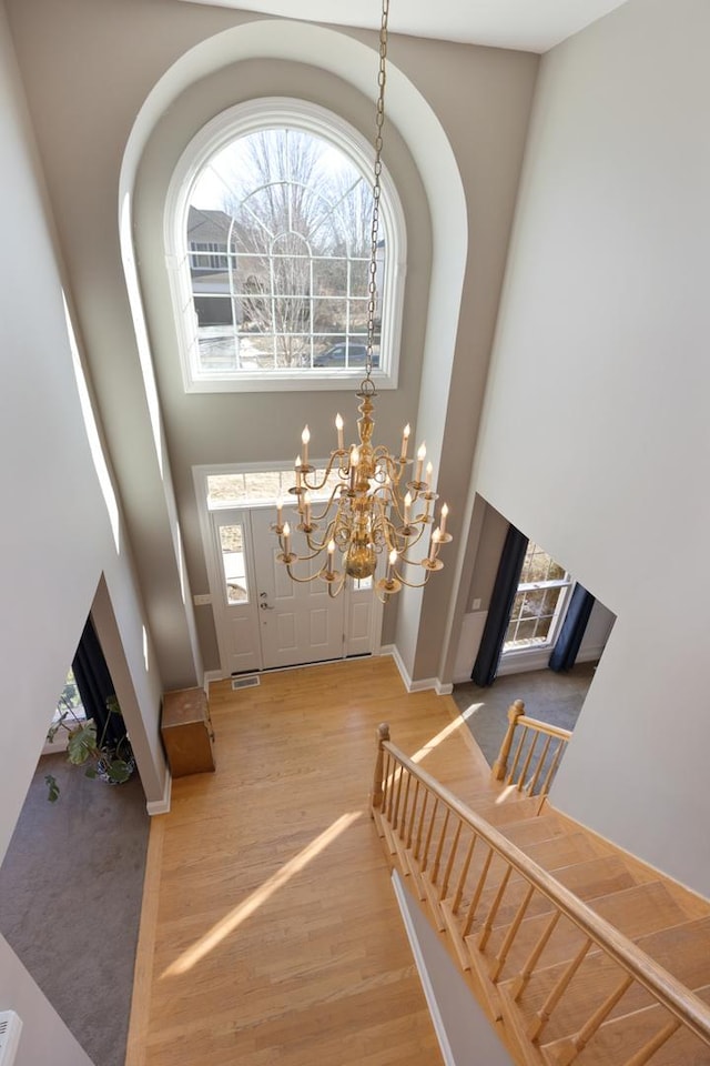 entryway featuring an inviting chandelier, wood-type flooring, a high ceiling, and plenty of natural light