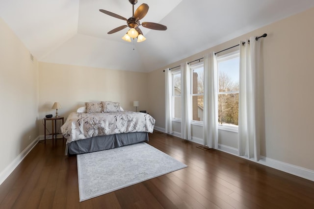 bedroom with a raised ceiling, lofted ceiling, dark hardwood / wood-style floors, and ceiling fan