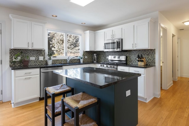 kitchen featuring stainless steel appliances, a kitchen island, white cabinets, and light hardwood / wood-style floors