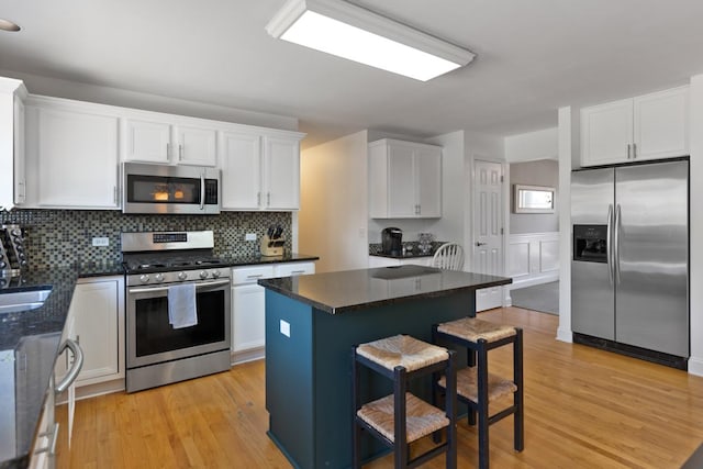 kitchen featuring stainless steel appliances, a kitchen breakfast bar, a center island, and white cabinets