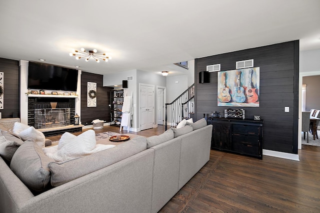 living room featuring dark wood-type flooring, a large fireplace, and wood walls