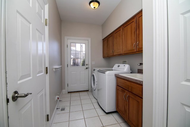 washroom with light tile patterned floors, sink, washer and clothes dryer, and cabinets