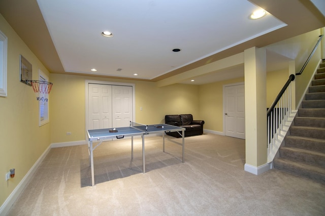 rec room with a raised ceiling and light colored carpet