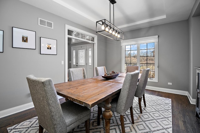 dining room featuring dark hardwood / wood-style flooring and a tray ceiling