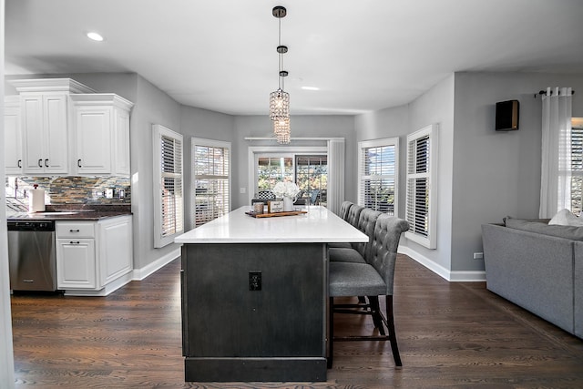 kitchen with dark wood-type flooring, white cabinetry, dishwasher, pendant lighting, and decorative backsplash