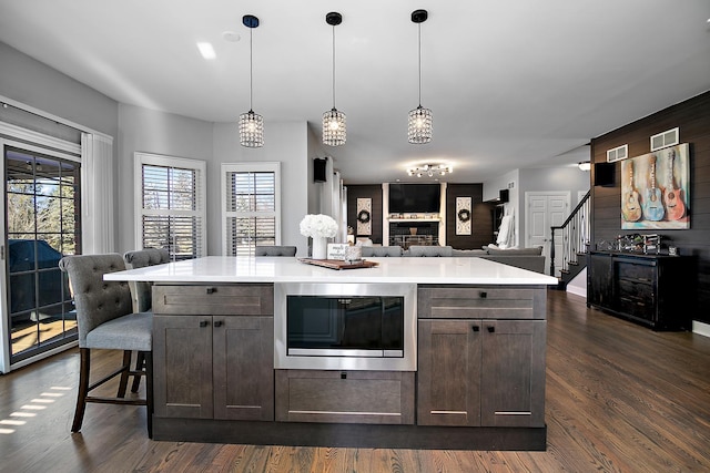 kitchen featuring black microwave, a healthy amount of sunlight, pendant lighting, and dark brown cabinetry