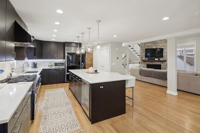 kitchen with a breakfast bar, pendant lighting, sink, a center island, and light hardwood / wood-style flooring