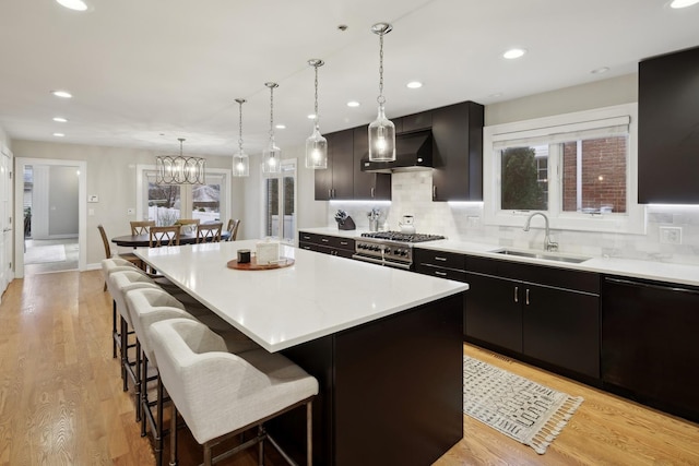 kitchen featuring pendant lighting, sink, a kitchen island, and wall chimney range hood