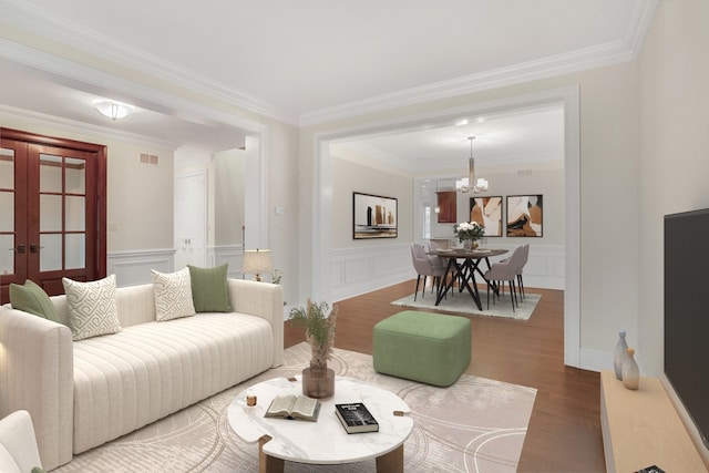 living room with crown molding, wood-type flooring, french doors, and a chandelier