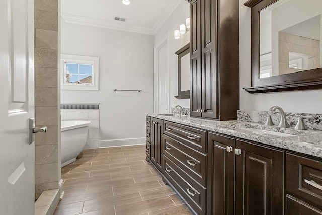 bathroom with ornamental molding, vanity, and a tub to relax in