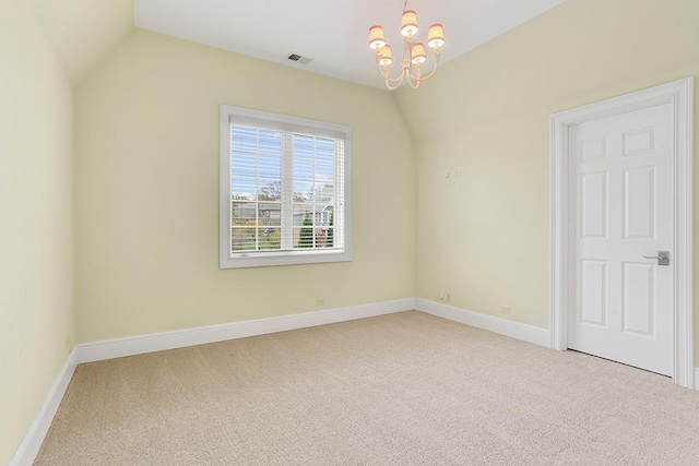 empty room featuring carpet flooring, a chandelier, and vaulted ceiling