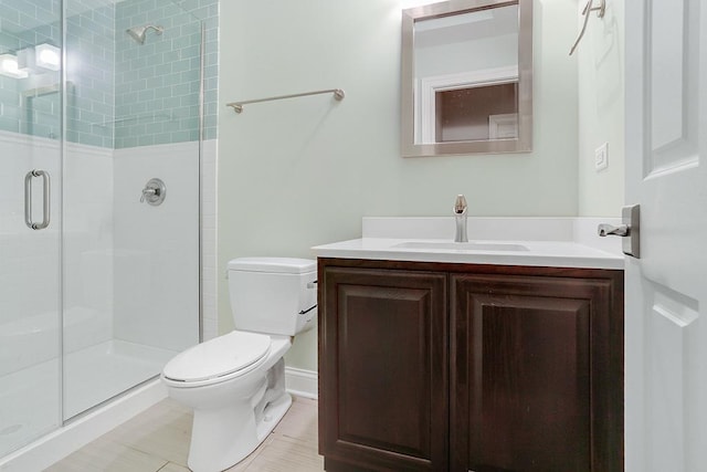 bathroom featuring vanity, a shower with door, and toilet