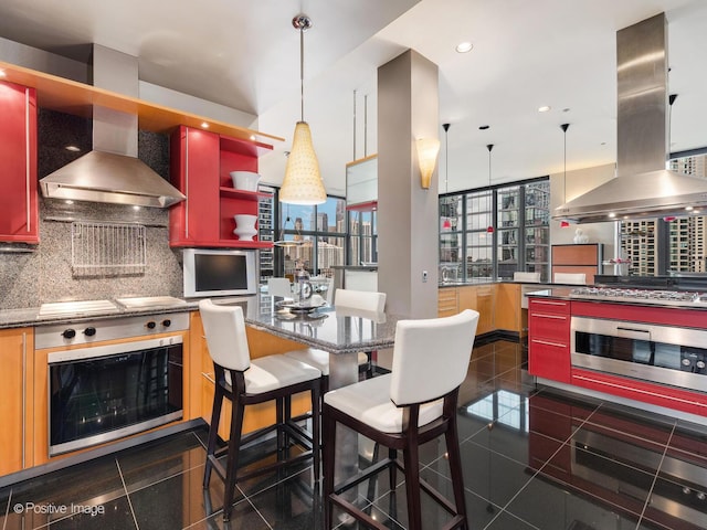 kitchen with wall chimney range hood, backsplash, stainless steel gas cooktop, island exhaust hood, and oven