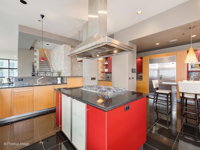 kitchen with appliances with stainless steel finishes, decorative light fixtures, sink, dark stone counters, and island exhaust hood