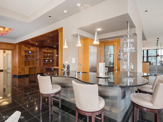 bar with pendant lighting, sink, and dark stone countertops