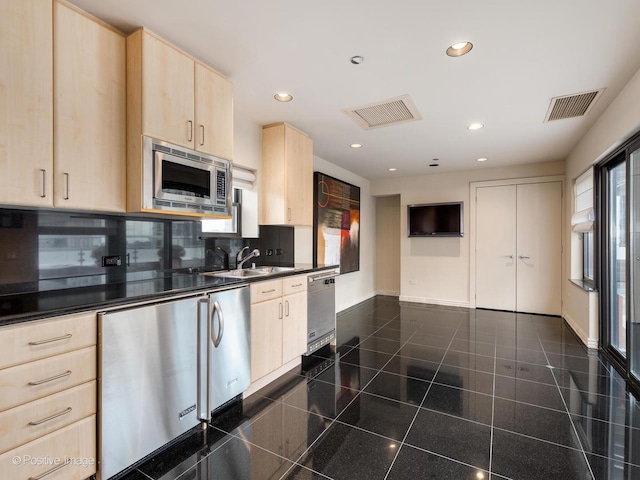 kitchen with stainless steel microwave, light brown cabinetry, tasteful backsplash, sink, and dishwashing machine