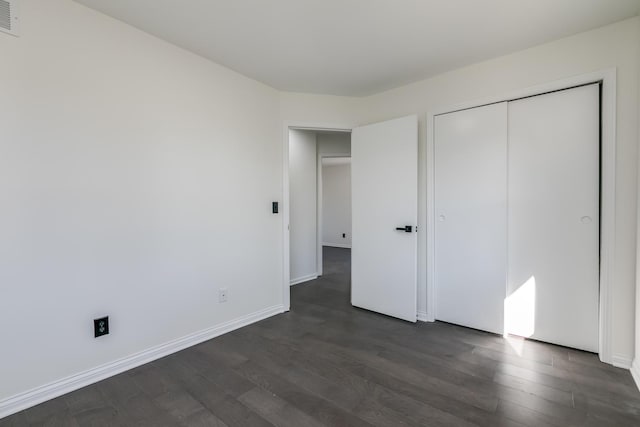 unfurnished bedroom with dark wood-type flooring and a closet