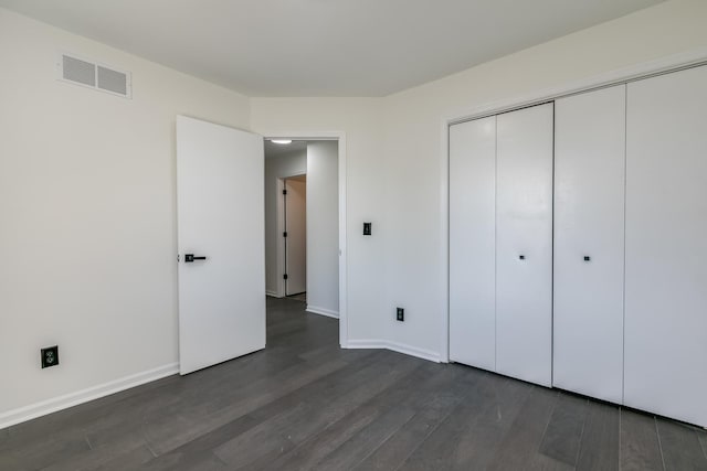 unfurnished bedroom with dark hardwood / wood-style flooring and a closet