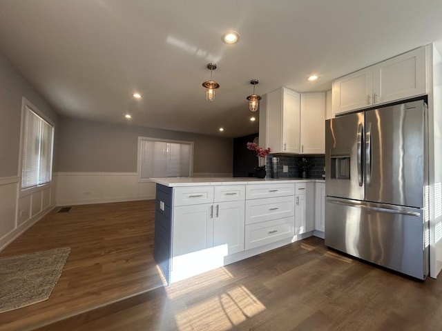 kitchen featuring white cabinetry, stainless steel refrigerator with ice dispenser, hanging light fixtures, and kitchen peninsula