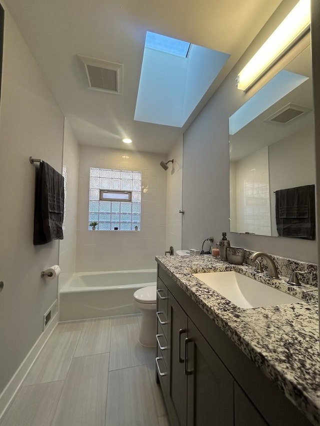 full bathroom featuring a skylight, vanity, tiled shower / bath combo, and toilet