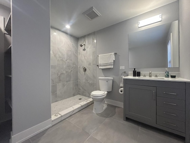 bathroom featuring vanity, tile patterned floors, toilet, and tiled shower