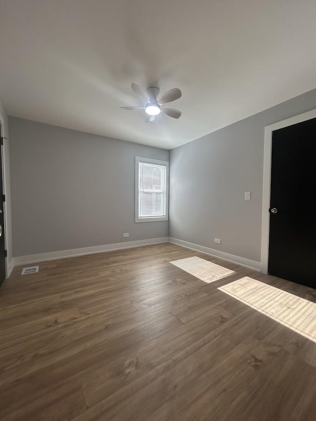 spare room with dark hardwood / wood-style flooring and ceiling fan