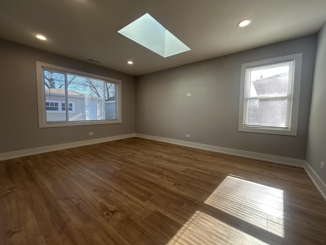 spare room featuring plenty of natural light, dark hardwood / wood-style flooring, and a skylight