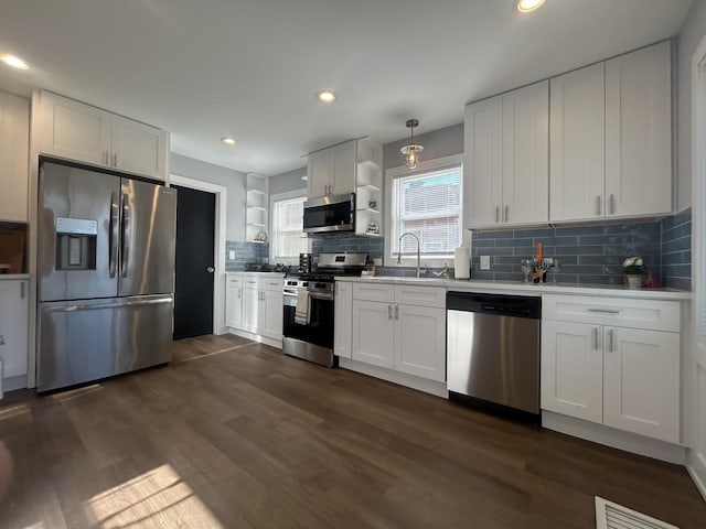 kitchen featuring white cabinetry, appliances with stainless steel finishes, backsplash, and decorative light fixtures